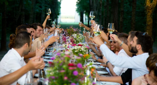 A long banquet table mid-celebration, guests standing to toast
